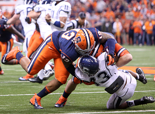 SU defensive tackle Deon Goggins and defensive end Robert Welsh bring down UConn running back Lyle McCombs for a loss of 4 yards. 