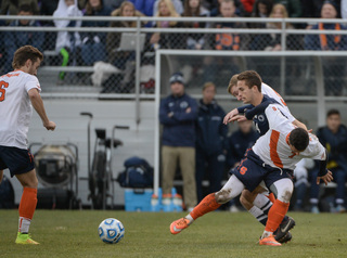 Syracuse midfielder Juuso Pasanen eyes a ball while Halis scraps with PSU's Brandon Savino.