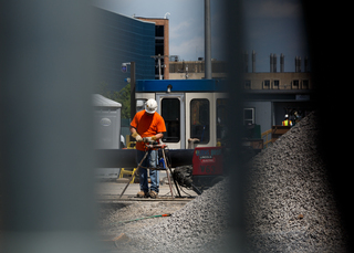 A construction worker can be seen through the fence on Waverly Avenue. Workers continue to update the sewer line along the street. Photo taken July 18, 2017