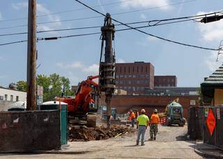 Construction crews watch as machinery drills into the ground along South Crouse Avenue. Photo taken July 18, 2017